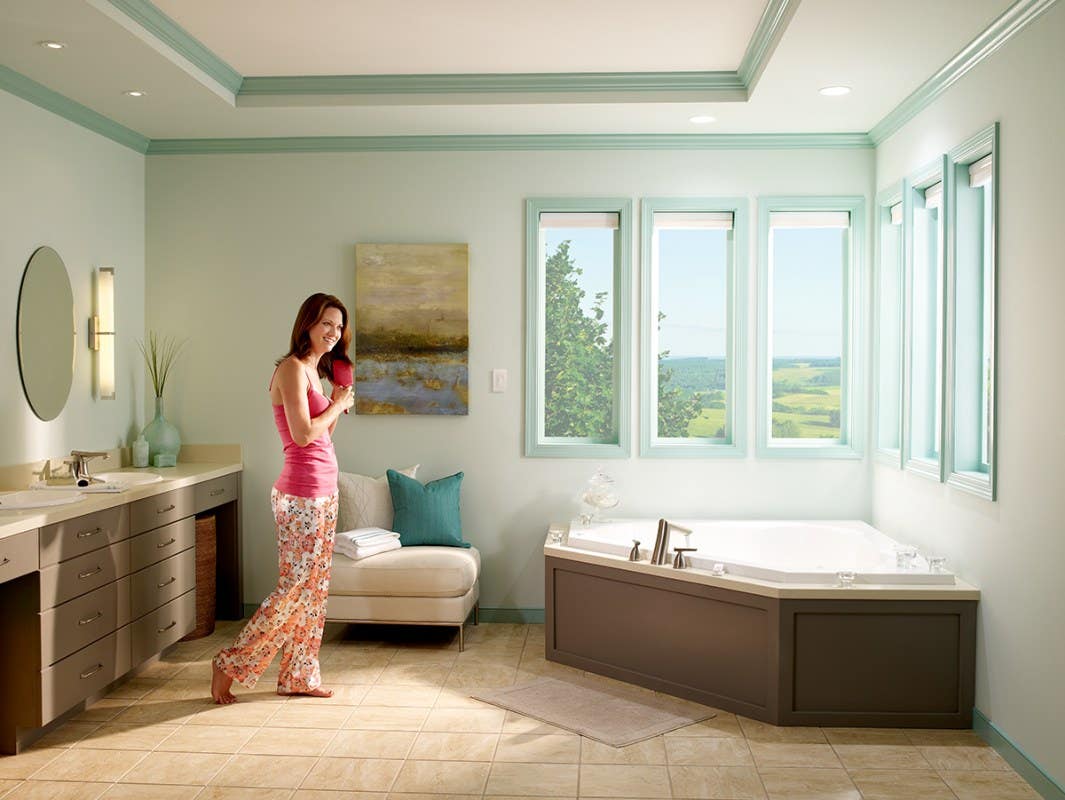 Woman in bathroom brushing her hair with opened light filtering honeycomb shades