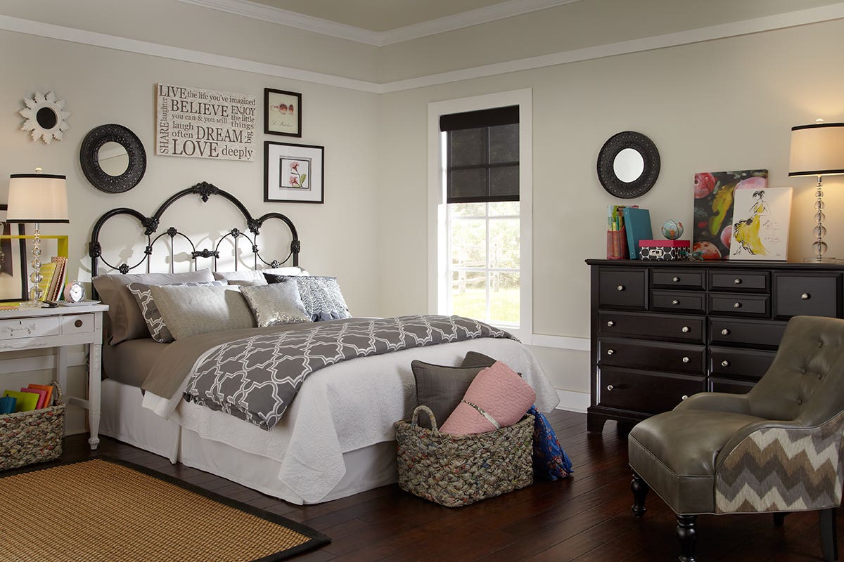 Young woman's bedroom with partially closed sheer roller shades in charcoal color