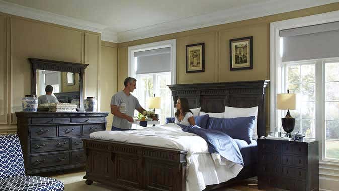 Couple in bedroom with dark gray furniture and white motorized window shades