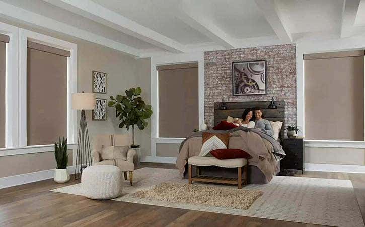 Smiling couple in bed with coffee and wireless roller blinds